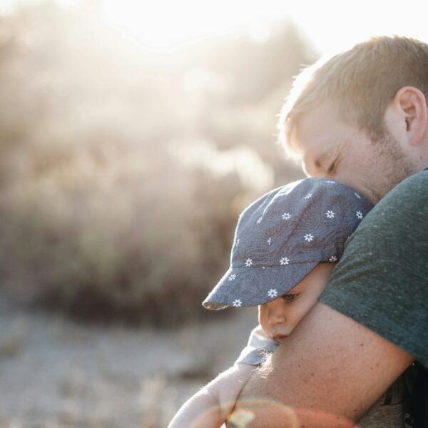 A father lovingly embraces his baby outdoors on a sunny day. Perfect for Father's Day themes.