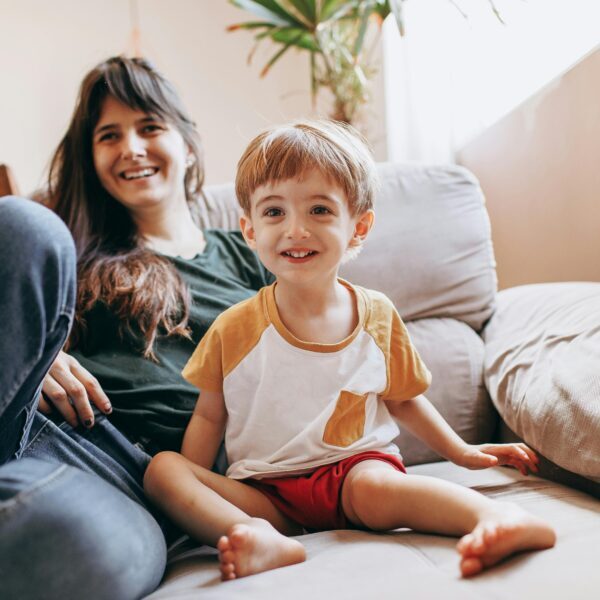 Mother and Son Smiling while Sitting on Living Room Couch