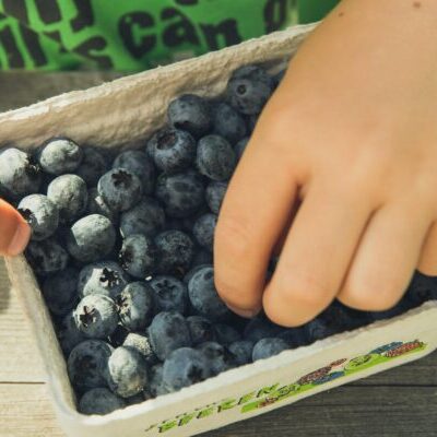 Person Holding Gray and Green Plastic Container With Black Beans