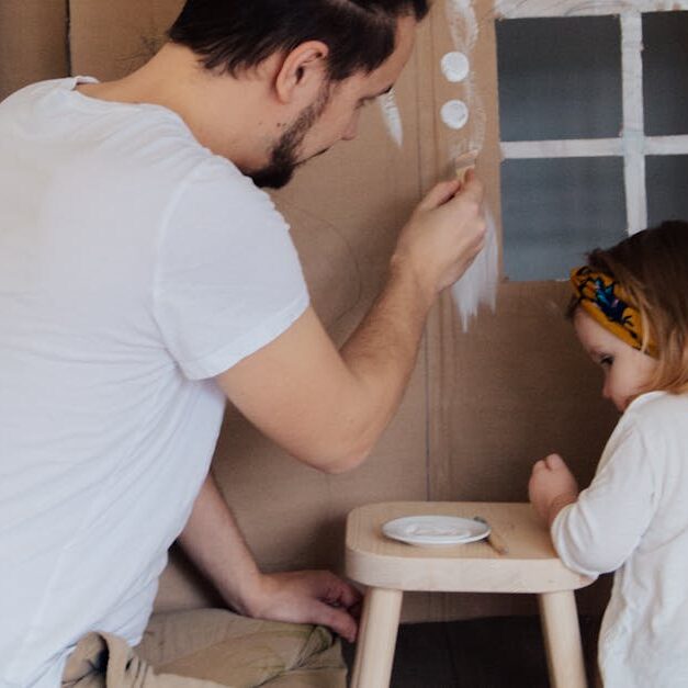 Father and Daughter Painting a Cardboard House Together