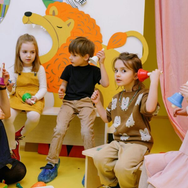 pexels-photo-8535230-8535230 Young children playing musical bells in a colorful classroom setting with a teacher.